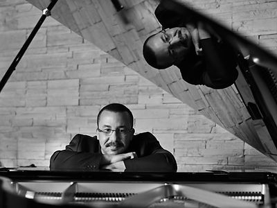 Thierry Vaton, regardant en face, posant; assis derrière un piano.