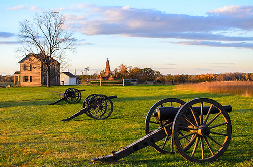 Cannons in a field with historic buildings in the background at Manassas National Battlefield Park in Virginia