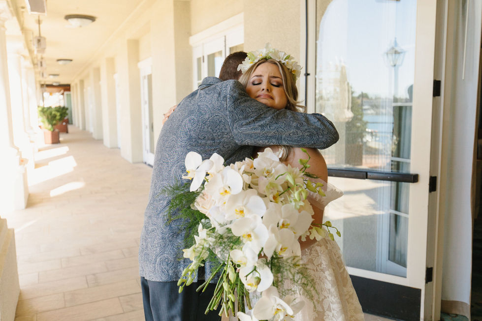 A Bride being hugged while holding a Curly Willow Curated and Designed Bouquet.