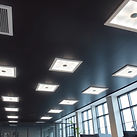 Office space with dark ceiling and bright lighting from square light sources in the ceilin