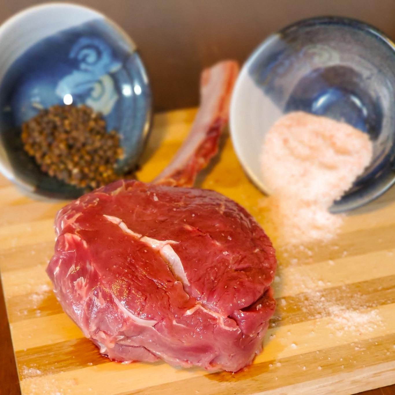 Fresh Bison Tomahawk Steak on a Cutting Board with Spices
