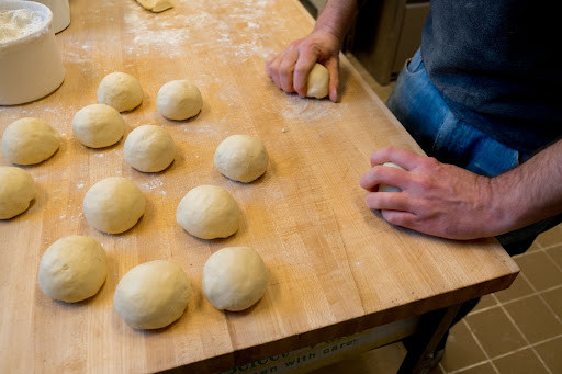 Baker at Leavened Bakery and Cafe in Cleveland rolls dough