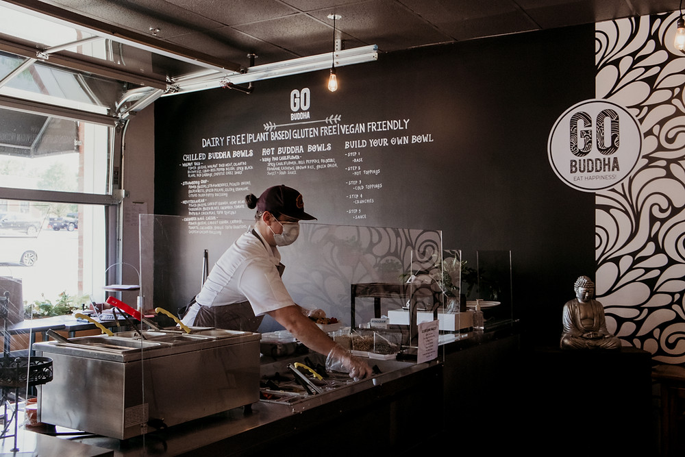 An employee at Go Buddha wears a mask while working behind the counter