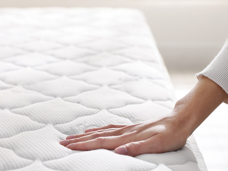 Woman touching soft mattress on bed indoors, closeup.jpg