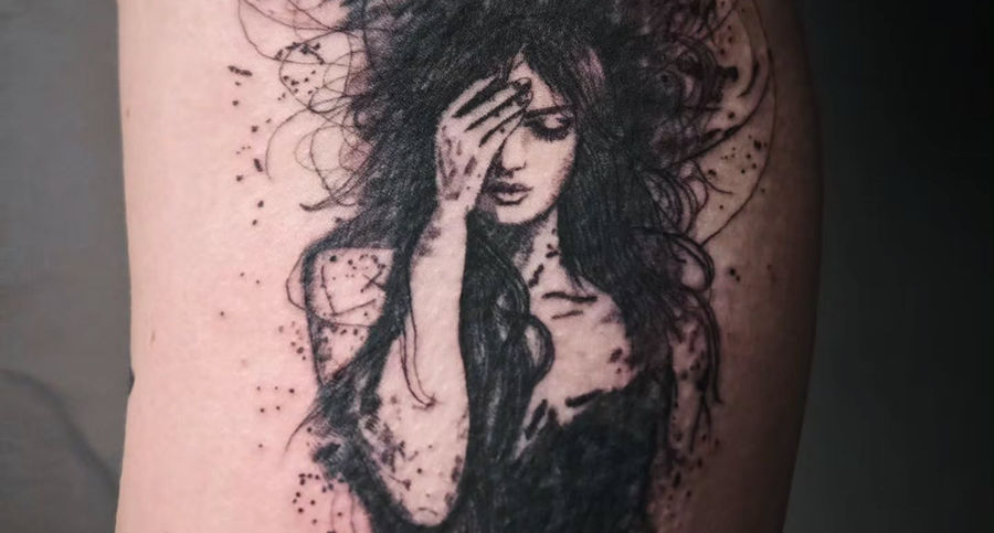 Dark woman portrait with loose expressive linework on thigh tattoo
