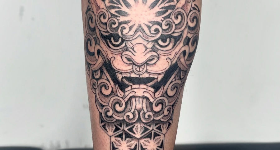 Bold ornamental oni mask within symmetrical forearm panel tattoo