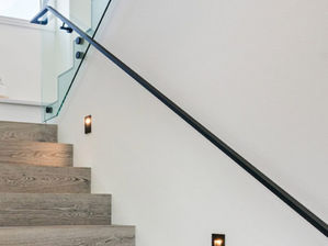 60339de348e0de8151617d6d_Glass-Stair-Railing-with-Matte-Black-hardware-and-Rail-Standoffs-