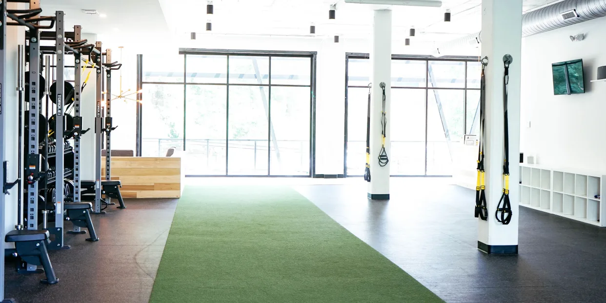 Turf lane with natural light and plants inside STAT Wellness Atlanta performance gym.
