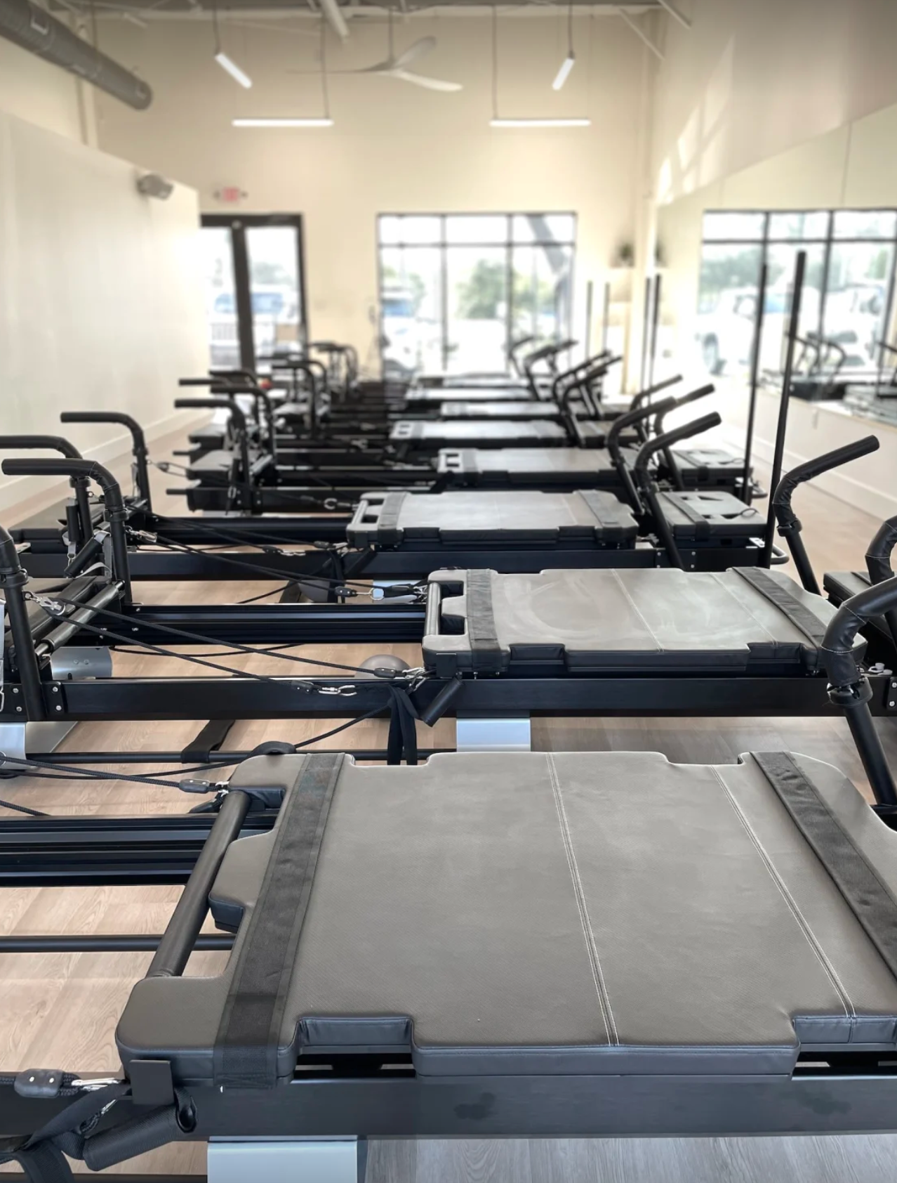 Empty reformer studio with mirrors and windows at Evolve Modern Pilates Charleston.