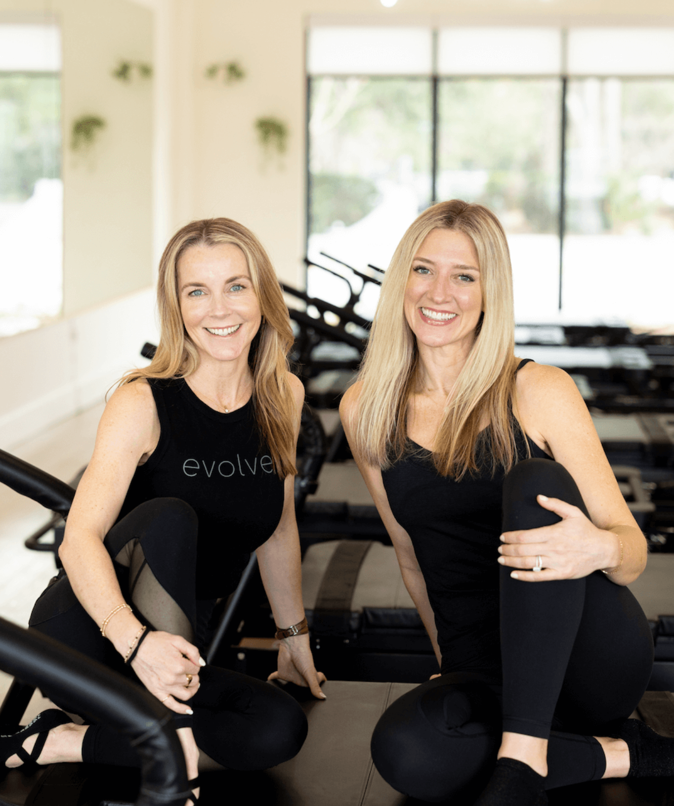 Co-owners of Evolve Modern Pilates Charleston sitting together in bright studio.