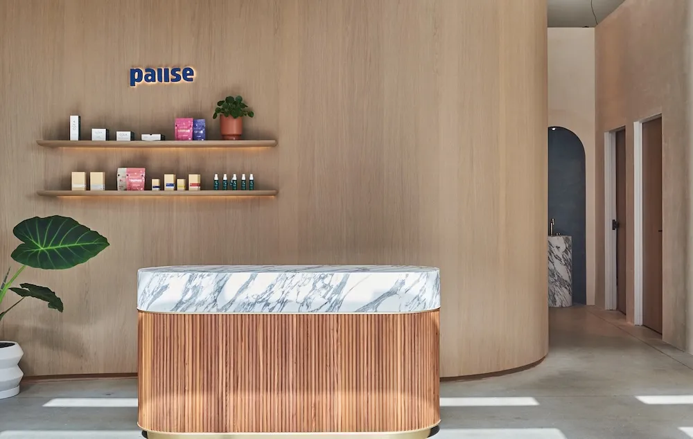 Minimalist lobby with oak desk and wellness retail shelves at Pause East Cobb Atlanta.