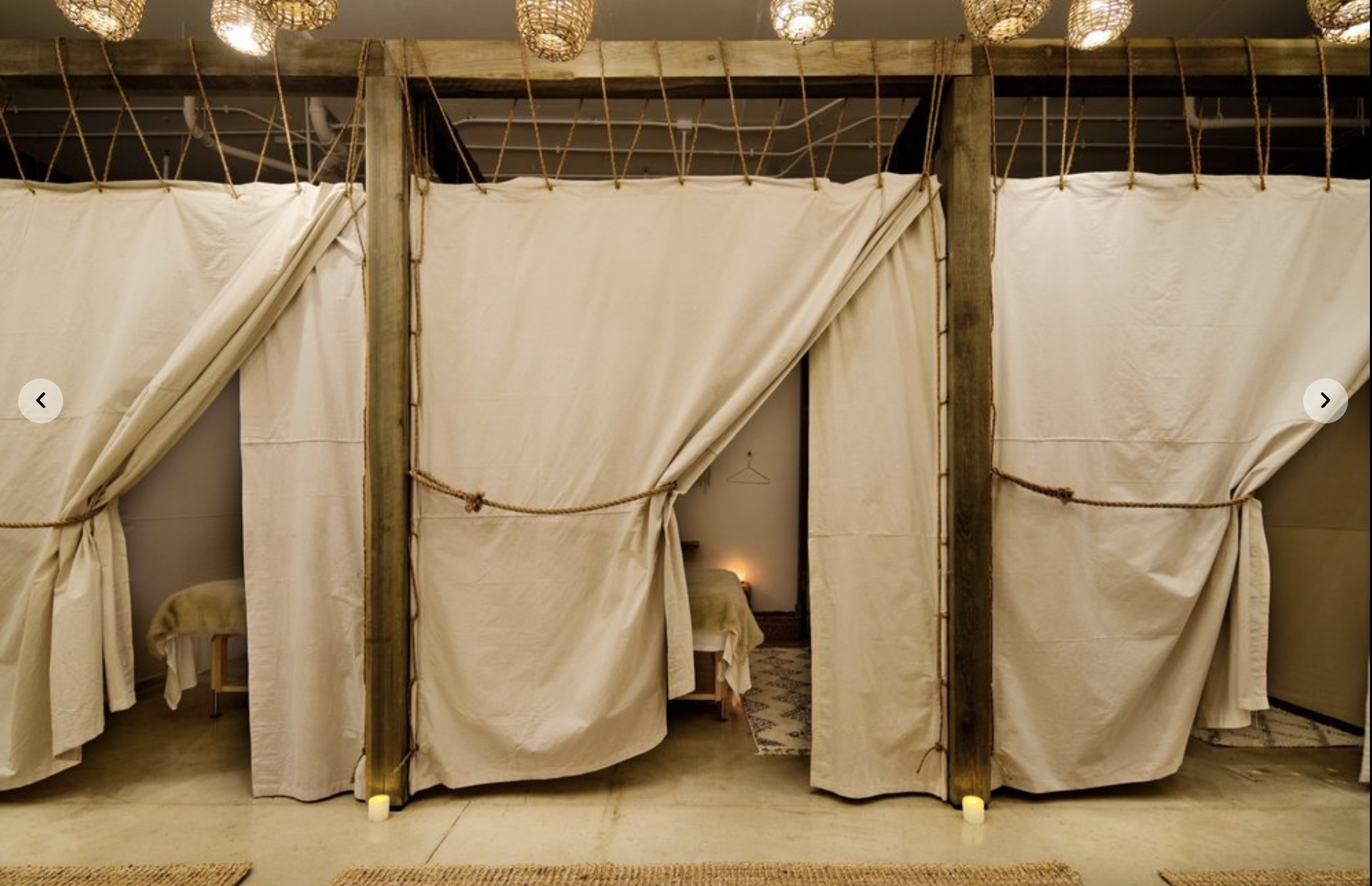 Row of curtained treatment nooks with wood beams at The NOW Massage Buckhead Atlanta.
