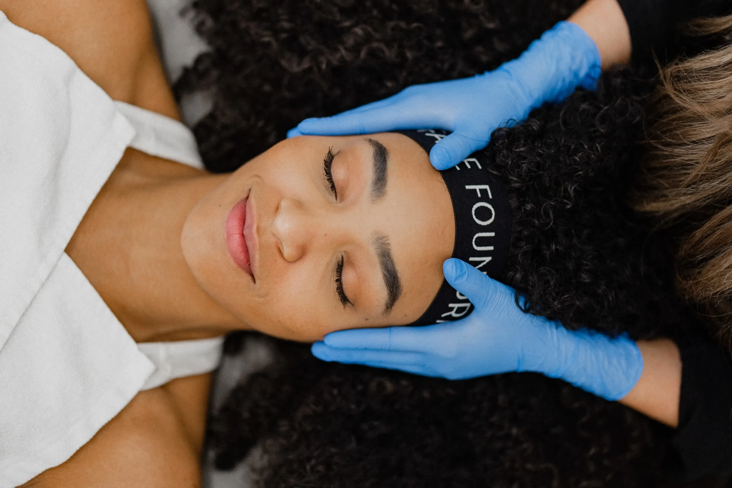 Client receives relaxing facial as esthetician applies serum with blue gloves at FACE FOUNDRIÉ Atlanta.