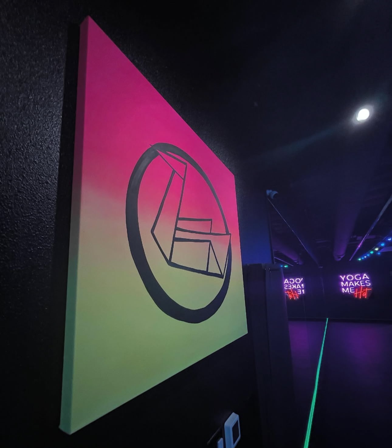 Illuminated Black Swan Yoga logo on multicolor neon panel inside Paradise Valley studio.