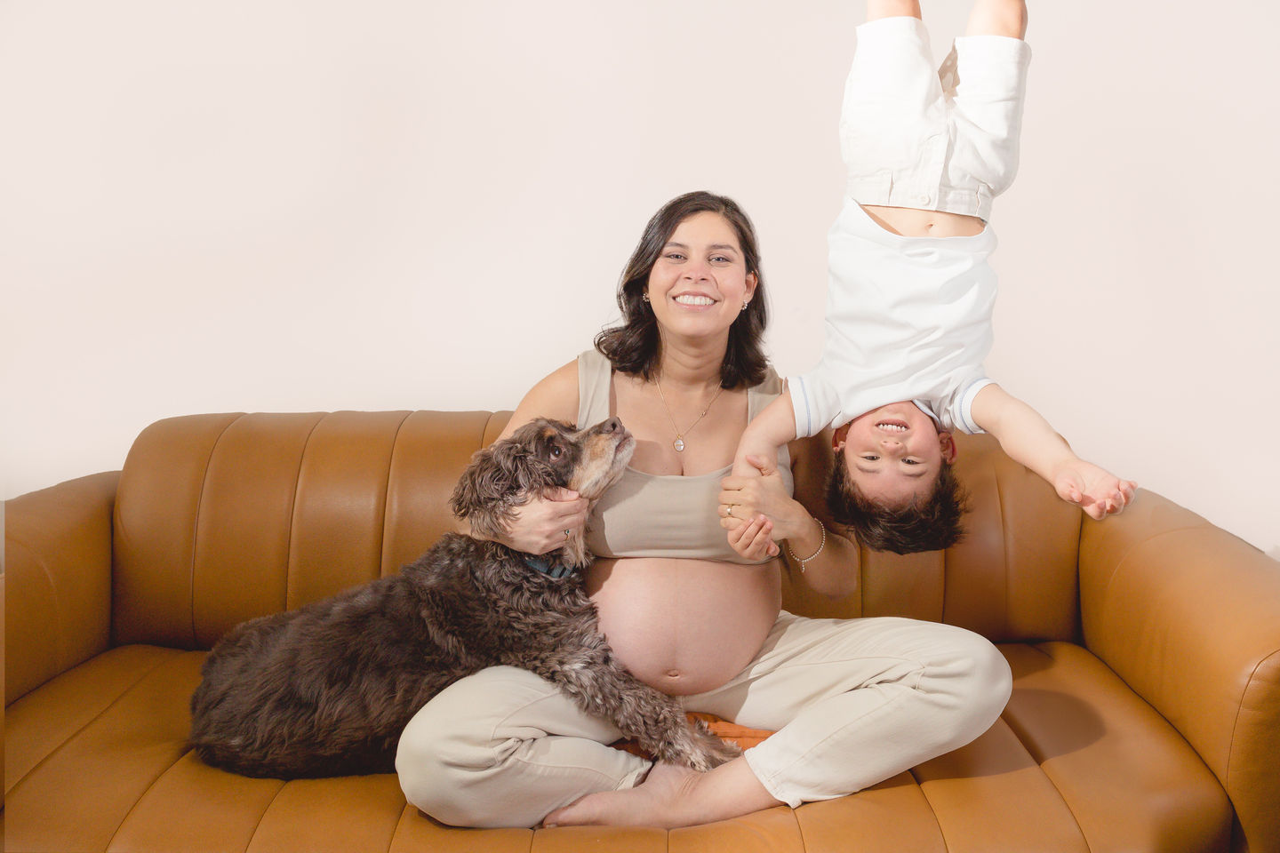 Pregnant woman with child and dog on a couch.