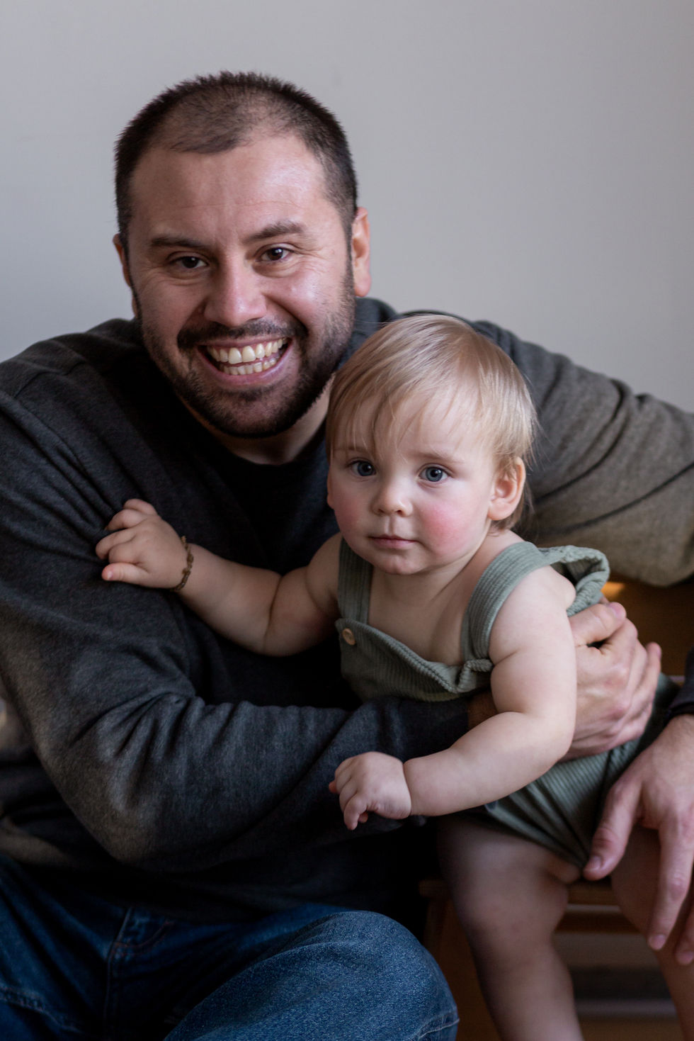 Smiling man holding a baby in his arms.