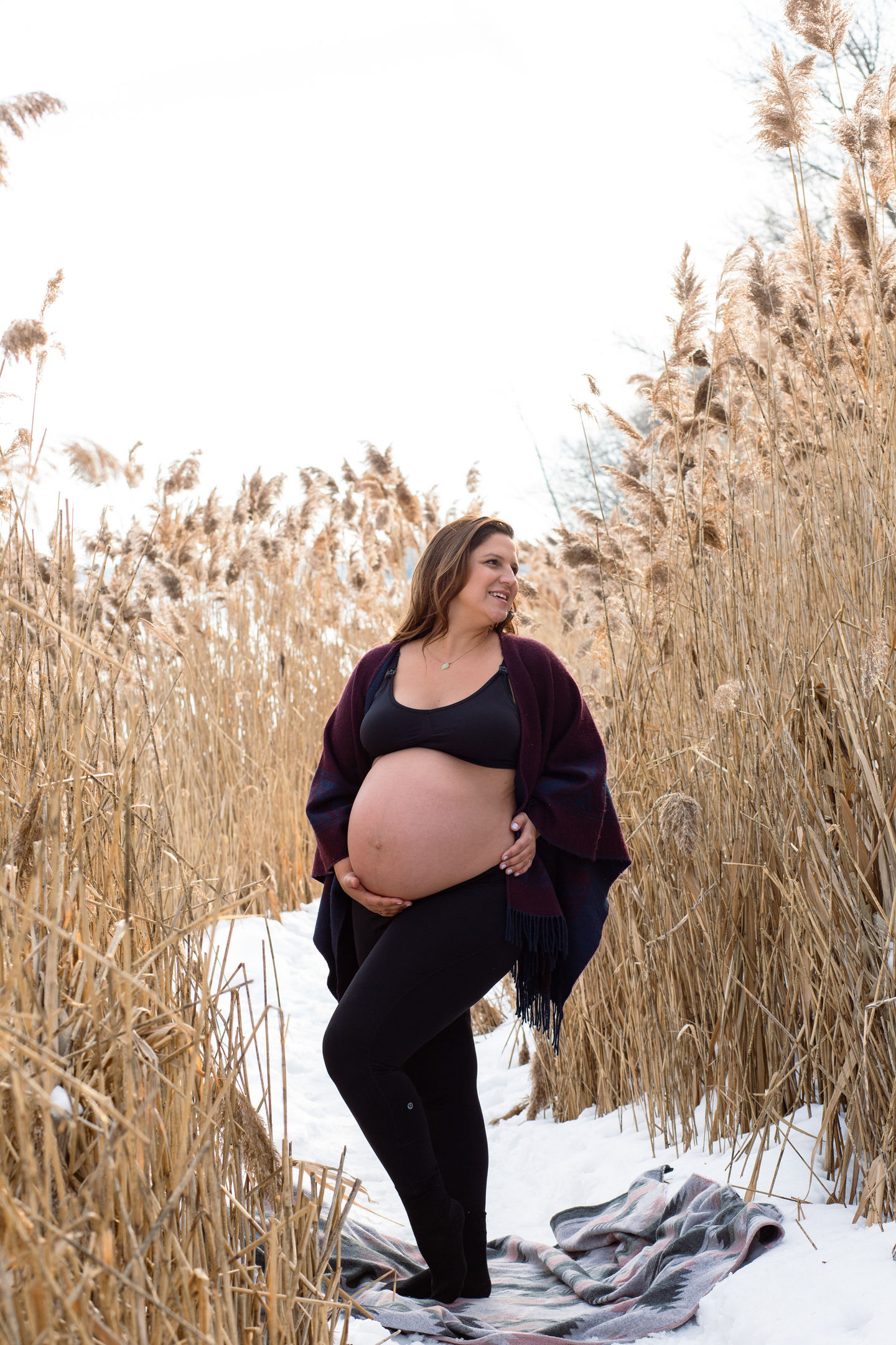 Pregnant woman standing in a field of tall grass.