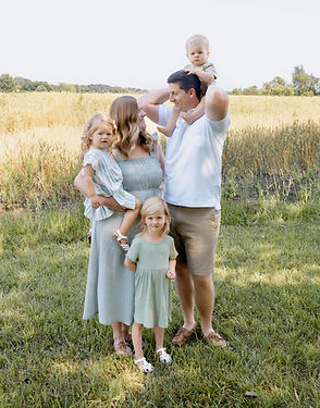 family of 5 embraces with mom and dad looking at eachother in Olathe, KS