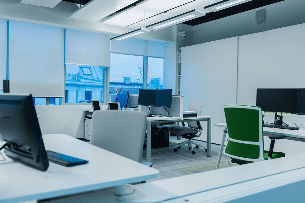 This image shows a contemporary open-plan office featuring clean white desks, computer monitors, ergonomic office chairs and large windows fitted with blinds. The workspace is bright, uncluttered and professionally maintained, demonstrating the high standards achieved through regular commercial office cleaning. Such environments help improve employee wellbeing, create a positive first impression for visitors and support a productive working atmosphere.