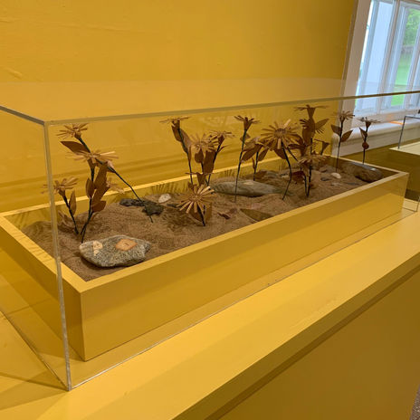 Flowers made out of ash wood in a bed of sand, stone tools scattered throughout