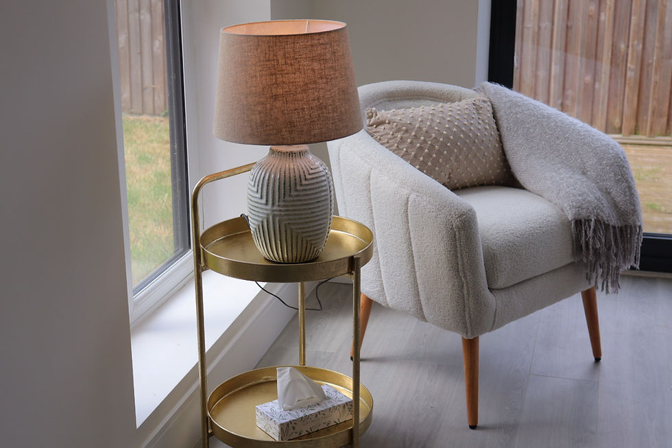 Gold side table and ceramic cream lamp and boucle cream sitting chair