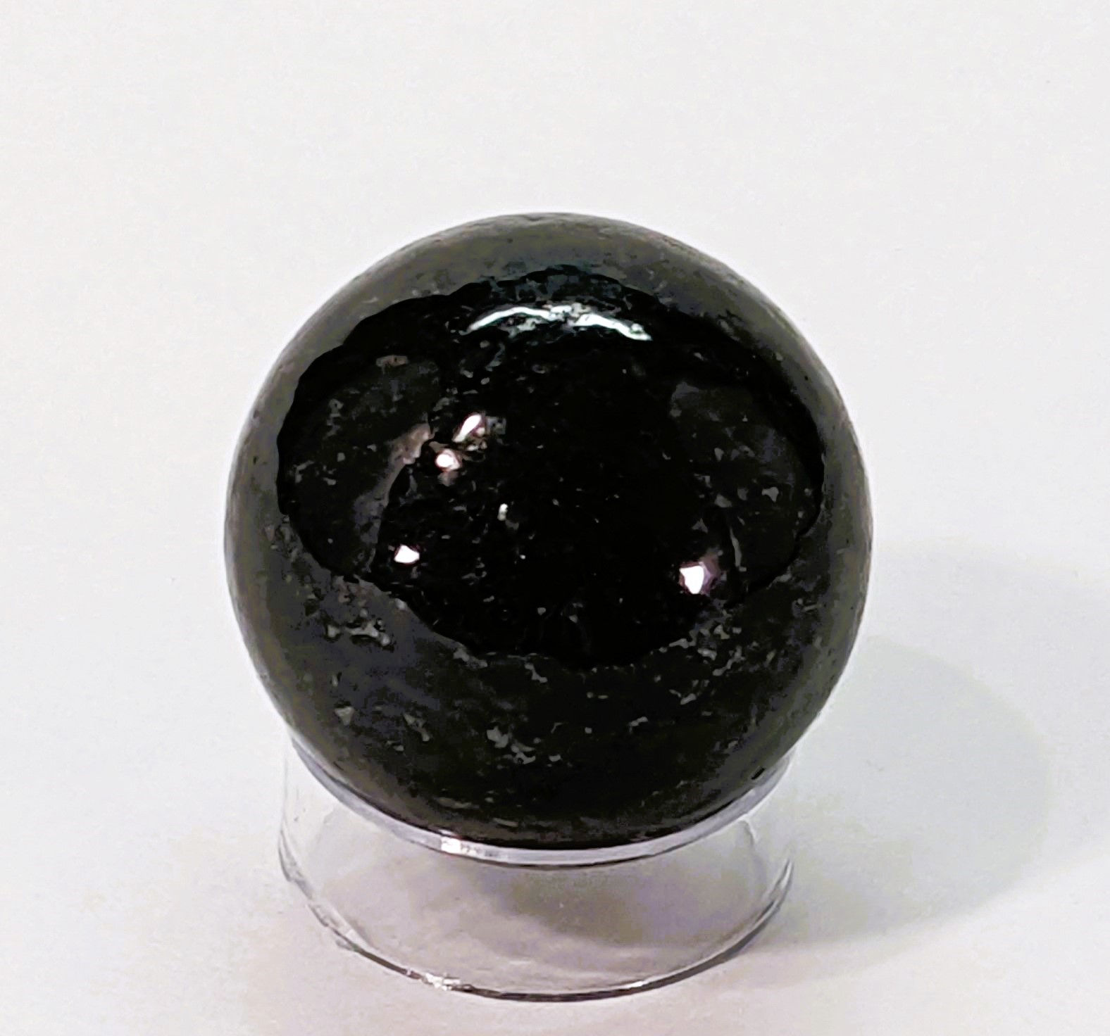 Polished Nuumite sphere with deep black and iridescent flashes of gold and green.
