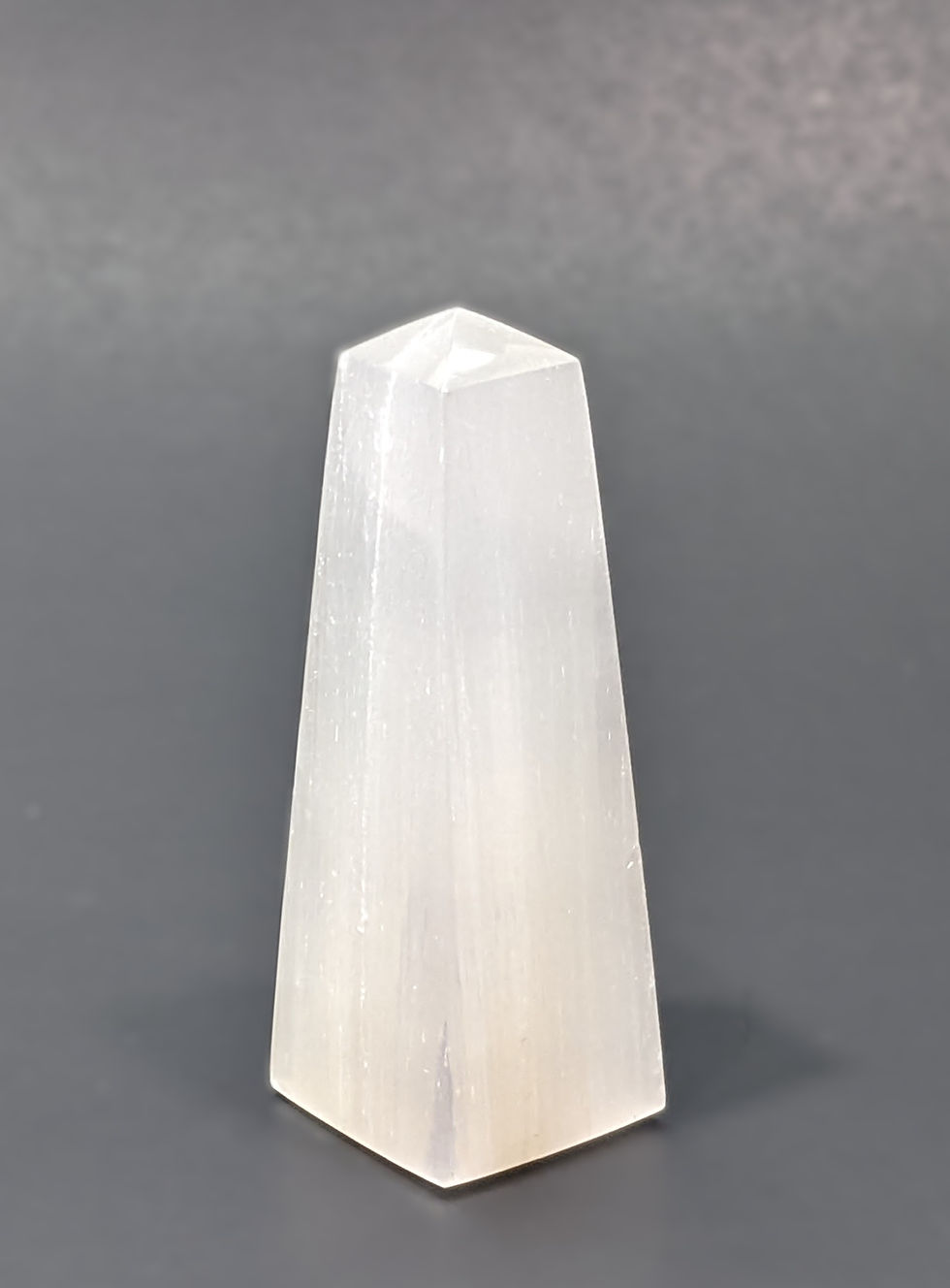 Natural Selenite obelisk standing upright on display