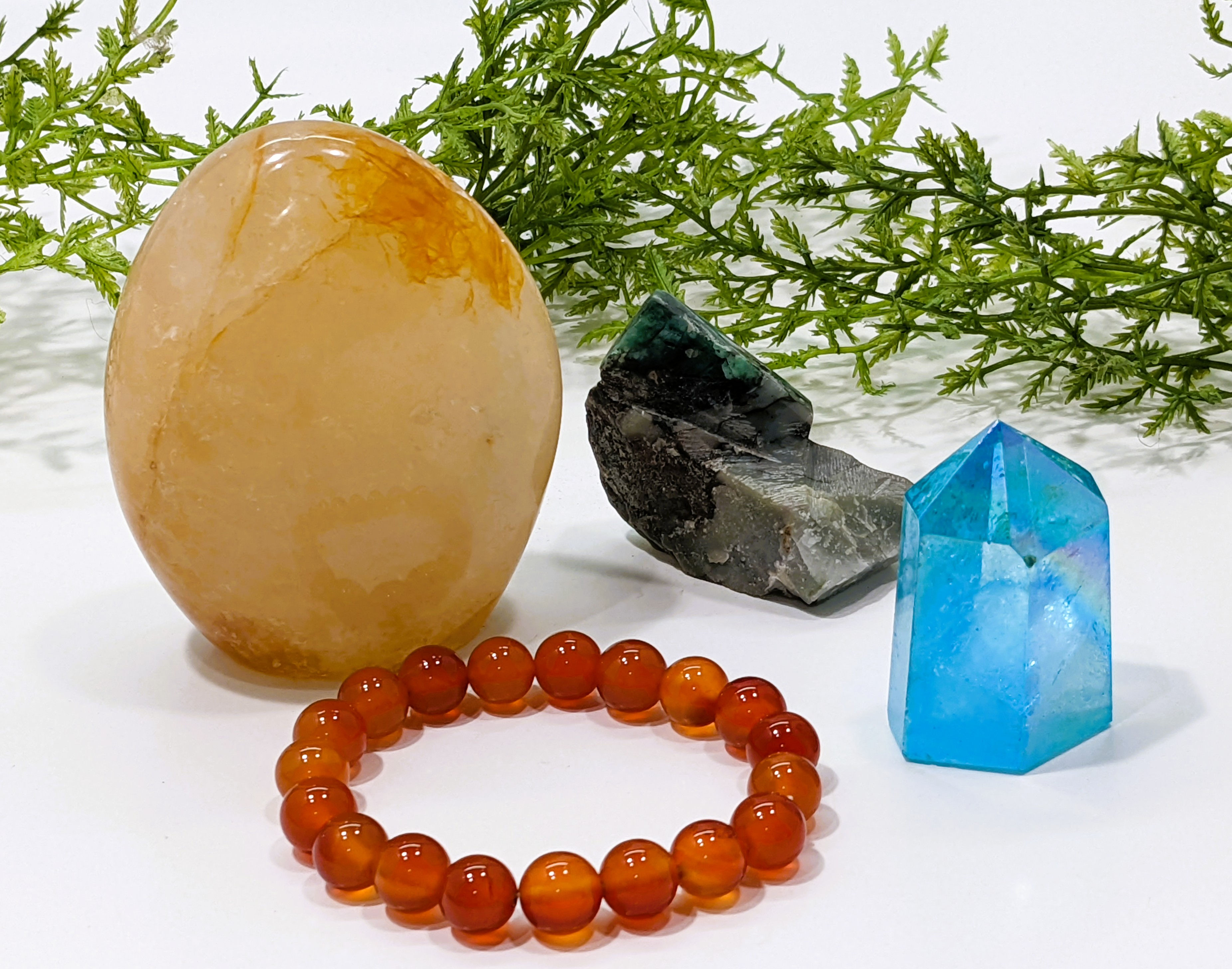 Aqua Aura tower, Carnelian bracelet, Emerald specimen, and Golden Healer Quartz freeform
