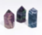 Rainbow Fluorite tower showcasing deep purples, greens, and teal bands.