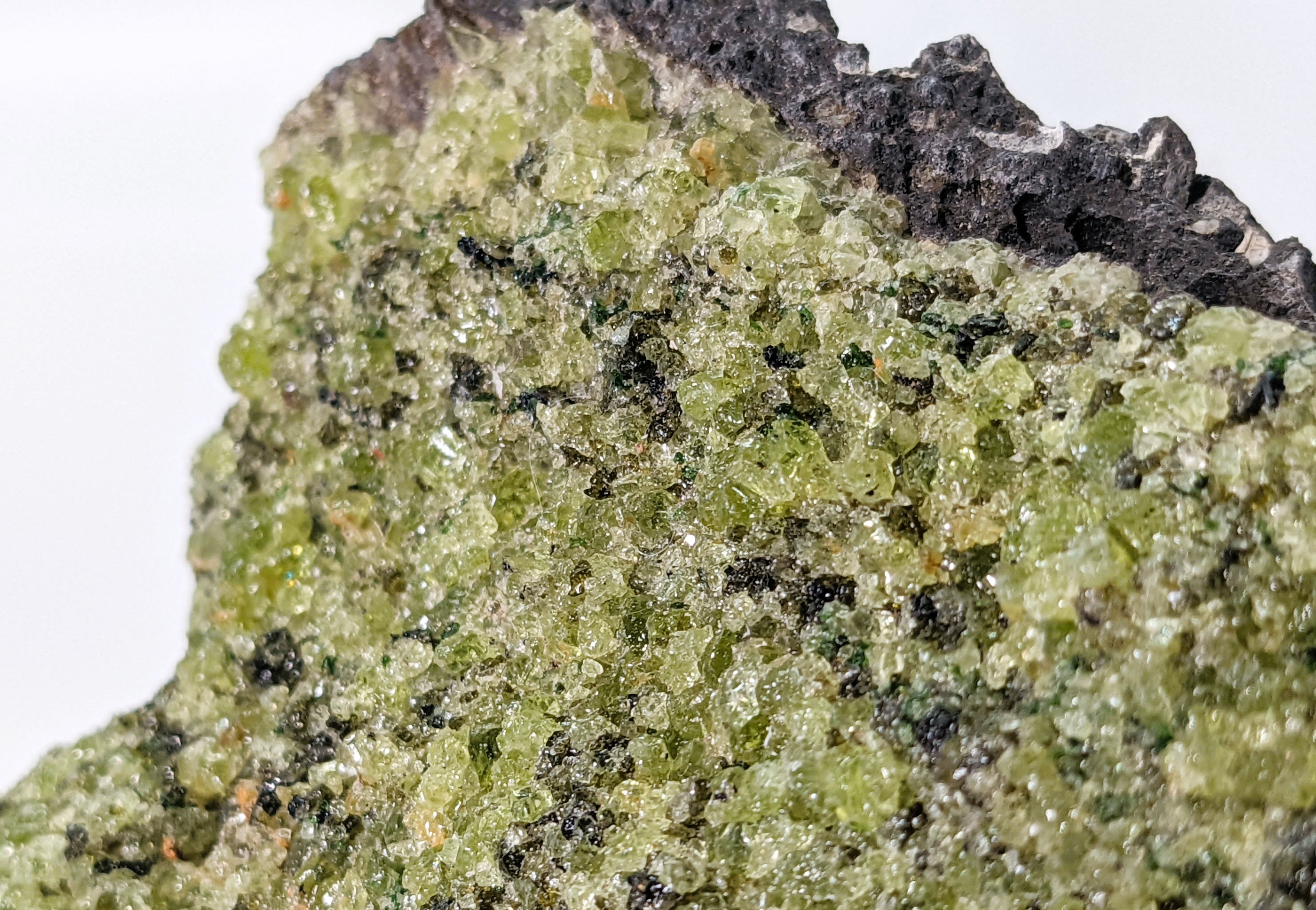 Unique Apache Peridot in basalt specimen, featuring sparkling peridot crystals against a rugged dark stone backdrop.