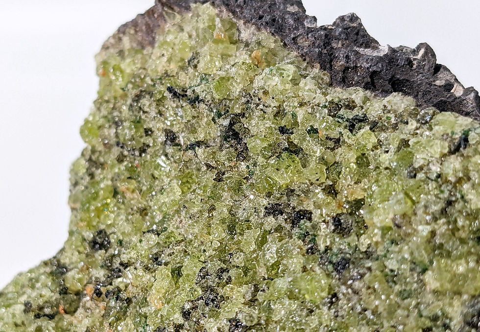 Unique Apache Peridot in basalt specimen, featuring sparkling peridot crystals against a rugged dark stone backdrop.