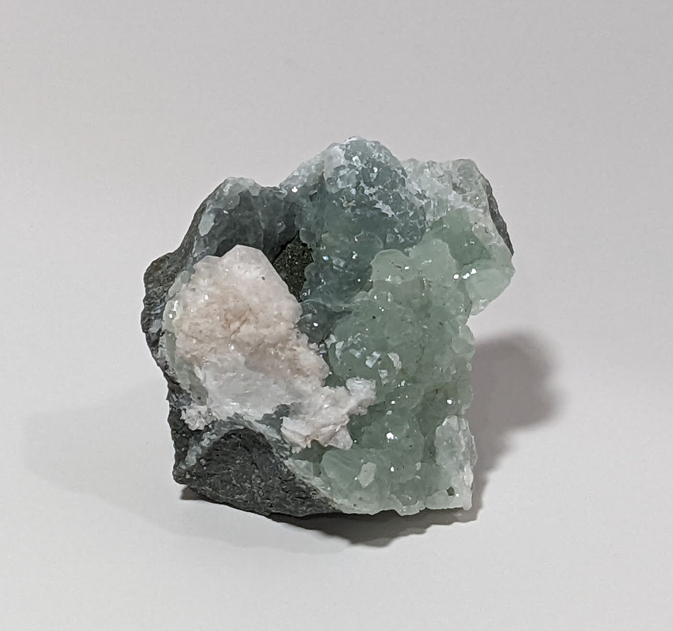 Unpolished Prehnite cluster showing pale green hues and earthy matrix