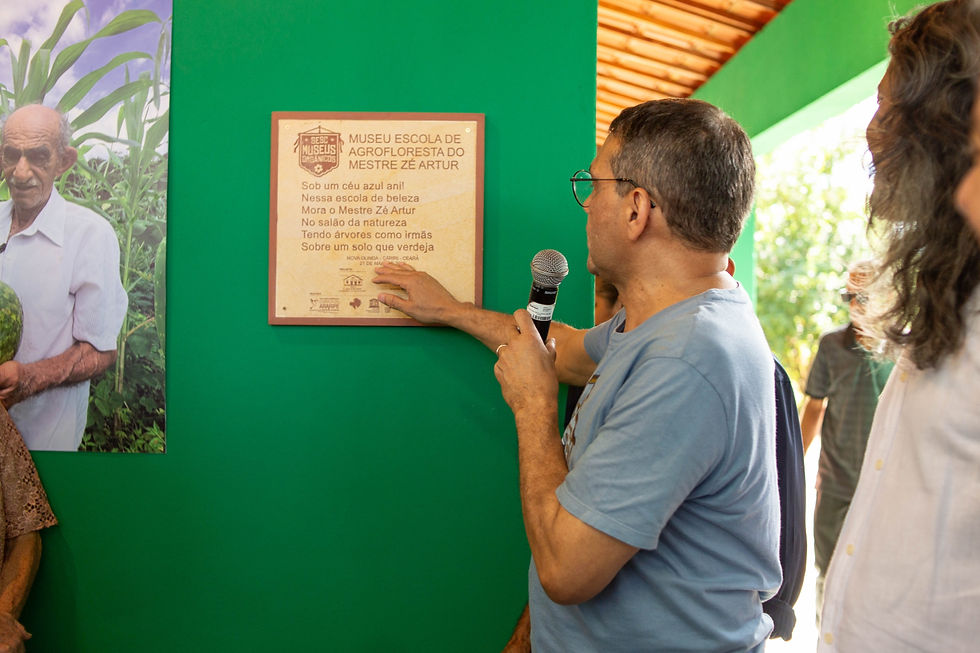 Alemberg Quindins apresentando a placa de reconhecimento do museu orgânico