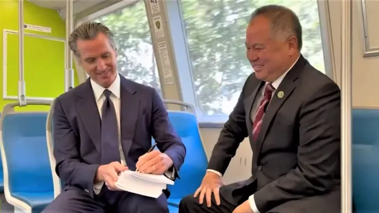 Gov. Gavin Newsom signs the state budget on a BART train in June with Assembly Budget Chairman Phil Ting.