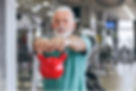 Personal trainer coaching senior man with kettlebell.