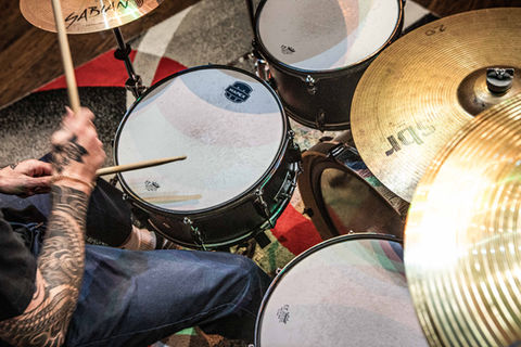 Tattooed arms of a drummer rehearsing in Studio D on Mapex drum heads.