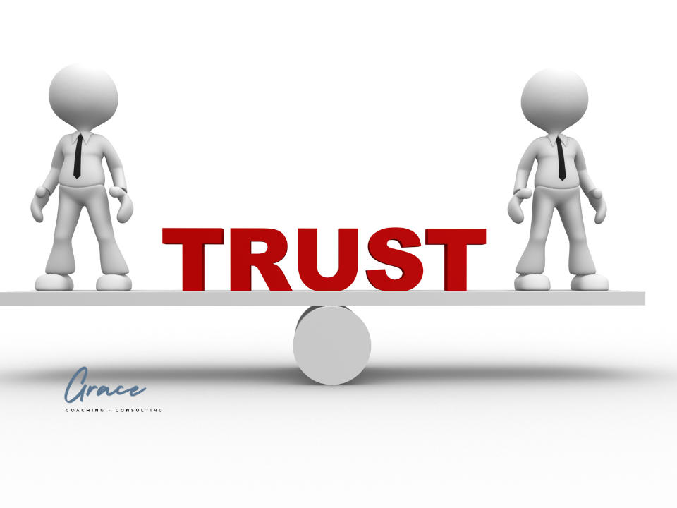 Two Humans in business attire on a balanced teeter tooter with the word trust in the middle