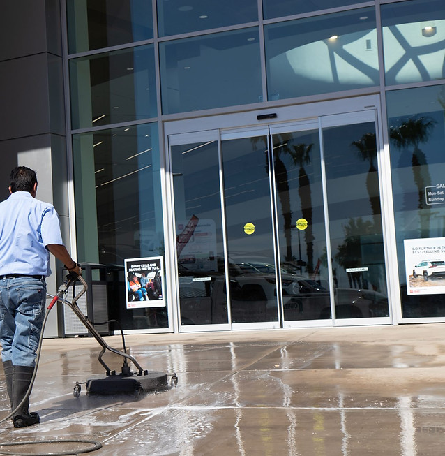 Professional pressure washing the entrance walkway of a commercial building