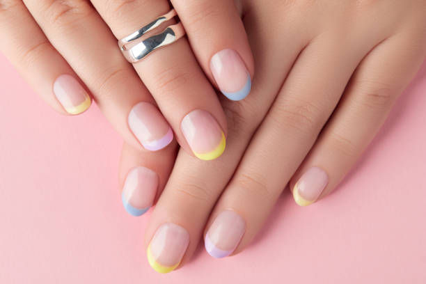 Hands with pastel yellow, blue, and purple French tip nails