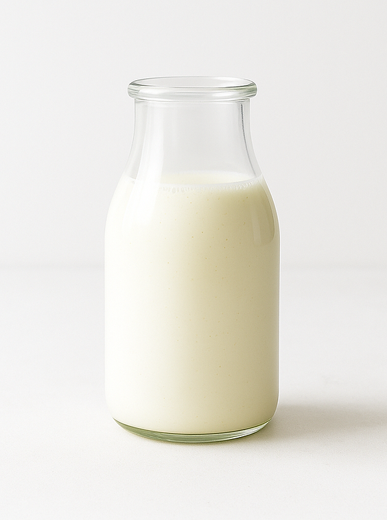 Glass bottle filled with homemade buttermilk substitute on a white background