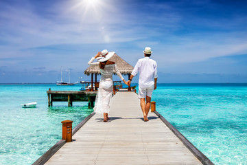Couple walking hand-in-hand on wooden pier over turquoise ocean