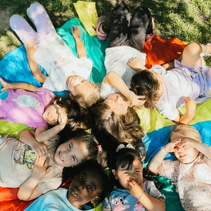 Children lying on colorful blankets in a circle.