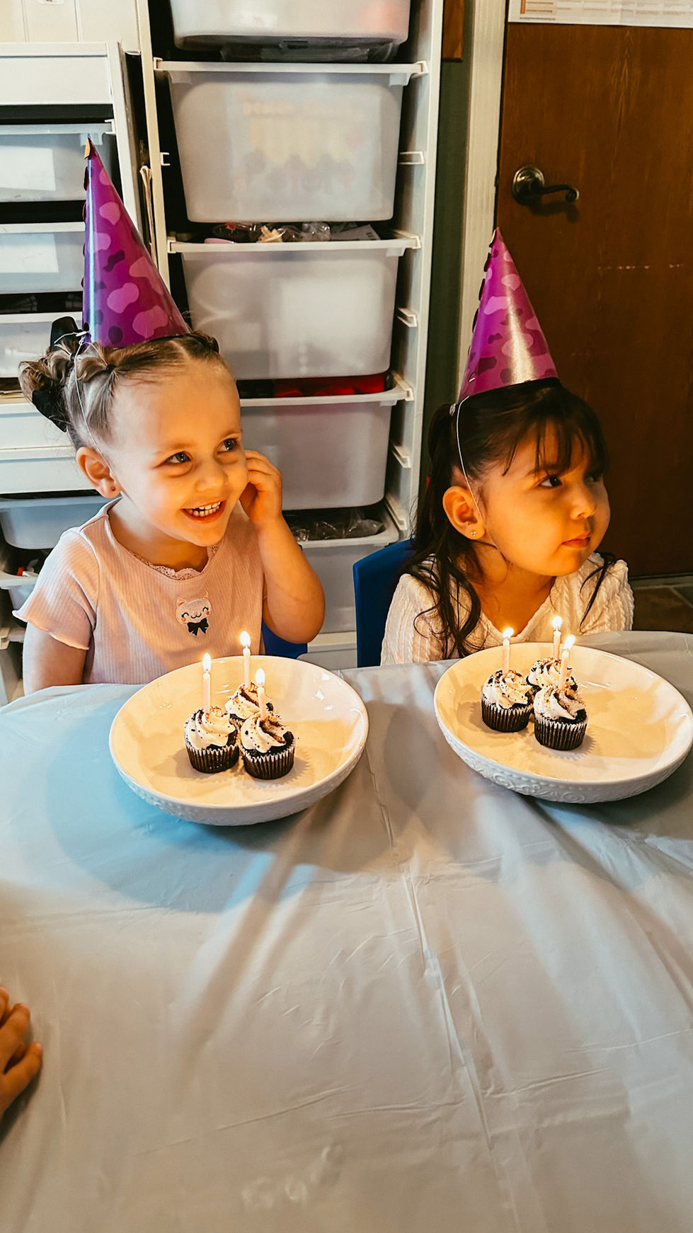 Two children with cupcakes and party hats.