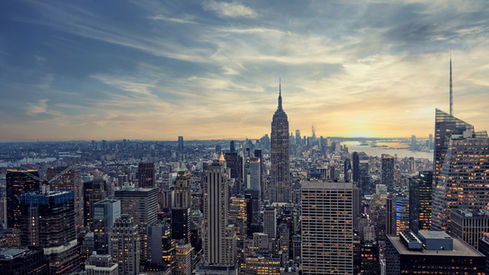 Stunning New York City skyline view from New Jersey at sunset, with vibrant orange and pink hues reflecting in the calm waters, creating a romantic and picturesque backdrop for an engagement proposal.