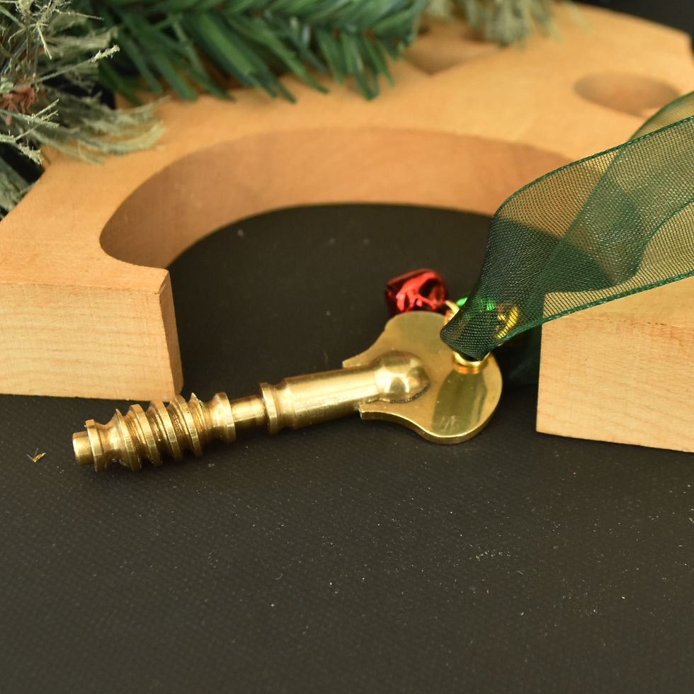 Handmade gold-toned upright bass tuning peg Christmas ornament hanging from gauzy dark green ribbon with red, gold, and green