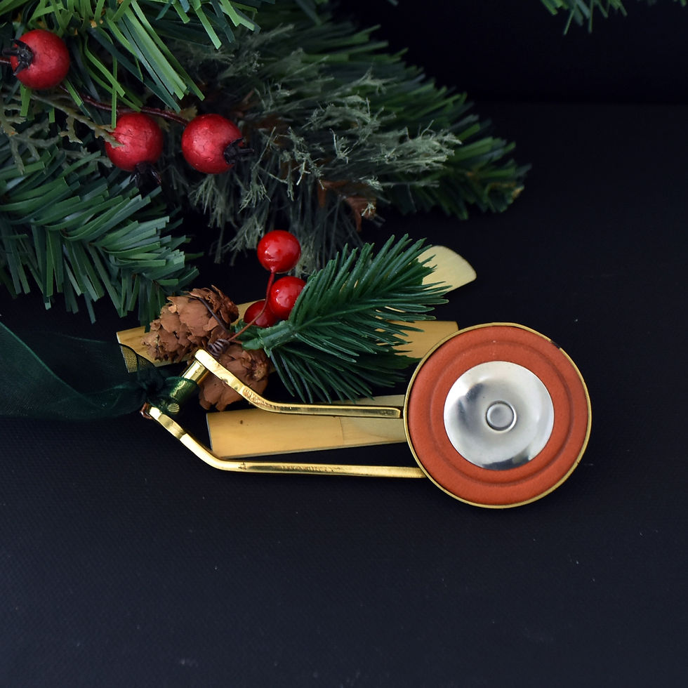 Handmade gold-toned saxophone key Christmas ornament hanging from dark green gossamer ribbon with holly berry and pinecone gr