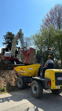 Bagger füllt Dumper mit Erde