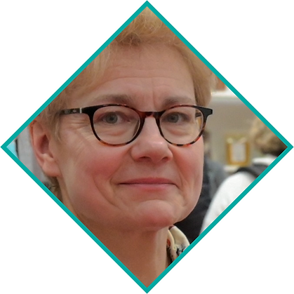 Sophie de Reynal smiling softly, set in a busy indoor environment. Image has a diamond-shaped teal border.