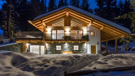 Timber ski chalet exterior surrounded by snowy forest in South Tyrol