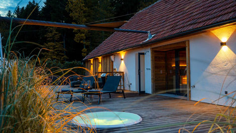 Weidehaus Deluxe exterior with private outdoor hot tub at dusk